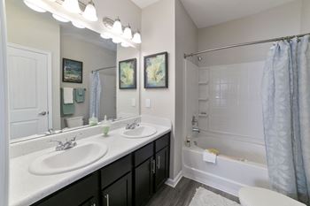 A bathroom with two sinks and a shower and a tub